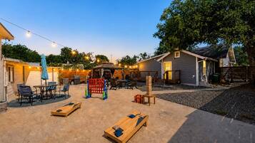 Patio con mobiliario exterior, un parque infantil de madera y una zona de estar cubierta.