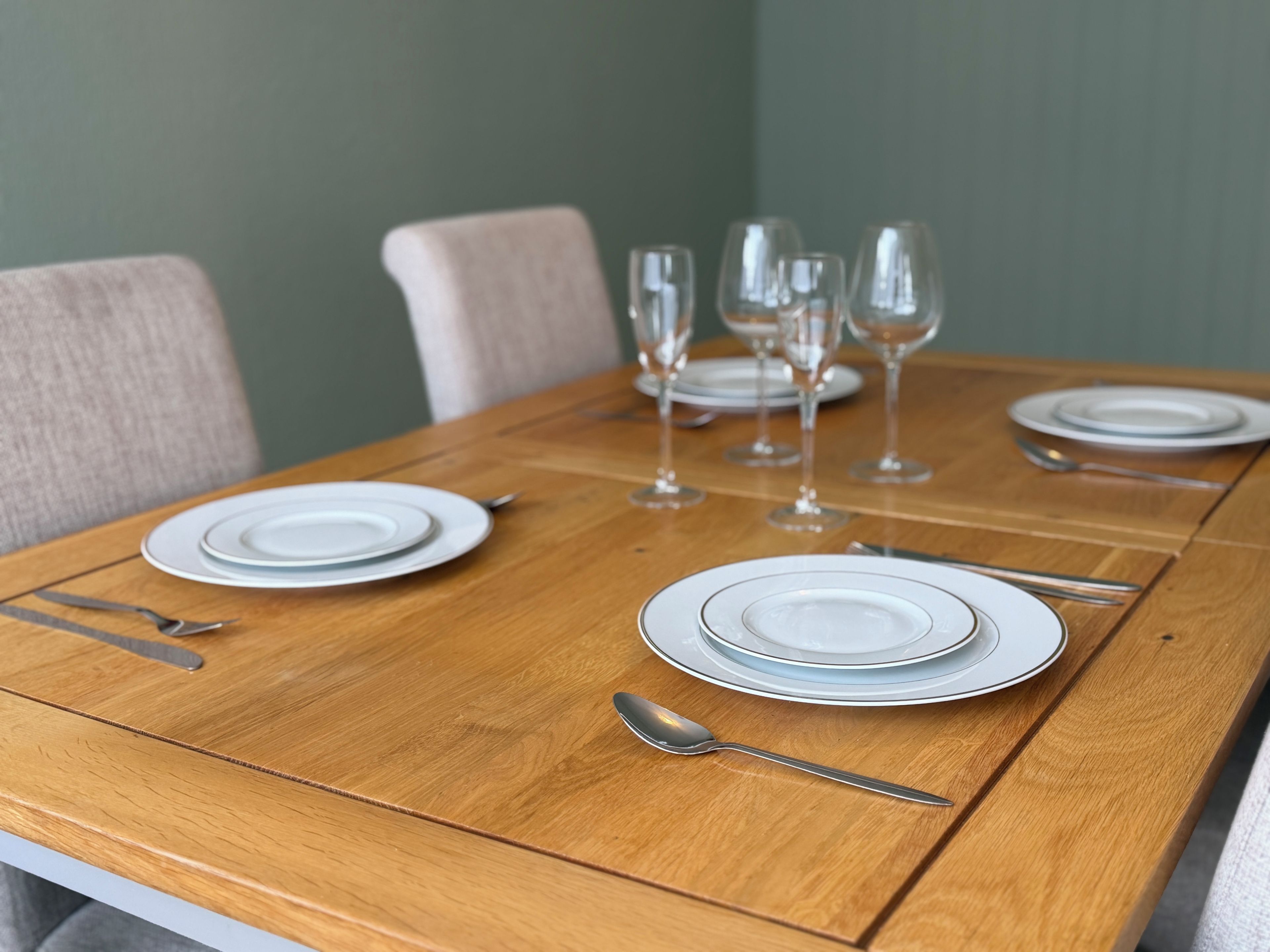 A dining table set with plates, cutlery, and wine glasses.