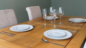 A dining table set with plates, cutlery, and wine glasses.