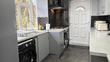 A compact kitchen with a washing machine, a sink, and a toaster.