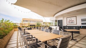 An outdoor dining area with tables and chairs, a canopy, and a view of buildings in the background. - GoUppers® Lujo en Pampatar Margarita Real (Pampatar)