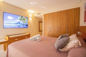 Een slaapkamer met een bed, een houten kledingkast, een bureau en een schilderij aan de muur.