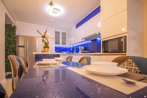 A modern kitchen with a blue countertop, white cabinets, and a built-in microwave. - GoUppers® Lujo en Pampatar Margarita Real (Pampatar)