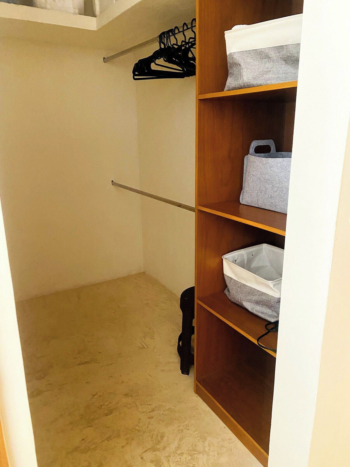 A closet with wooden shelves, a hanging shoe rack, and a black bag.