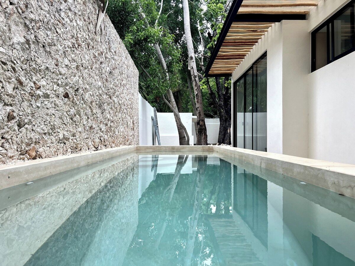 A swimming pool with a stone wall and a modern building in the background.