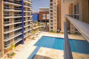Ein mehrstöckiges Gebäude mit Pool auf dem Dach, Balkonen und blauem Himmel.