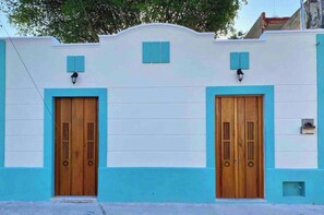 Un bâtiment doté de deux portes en bois et d’une façade bleu clair.