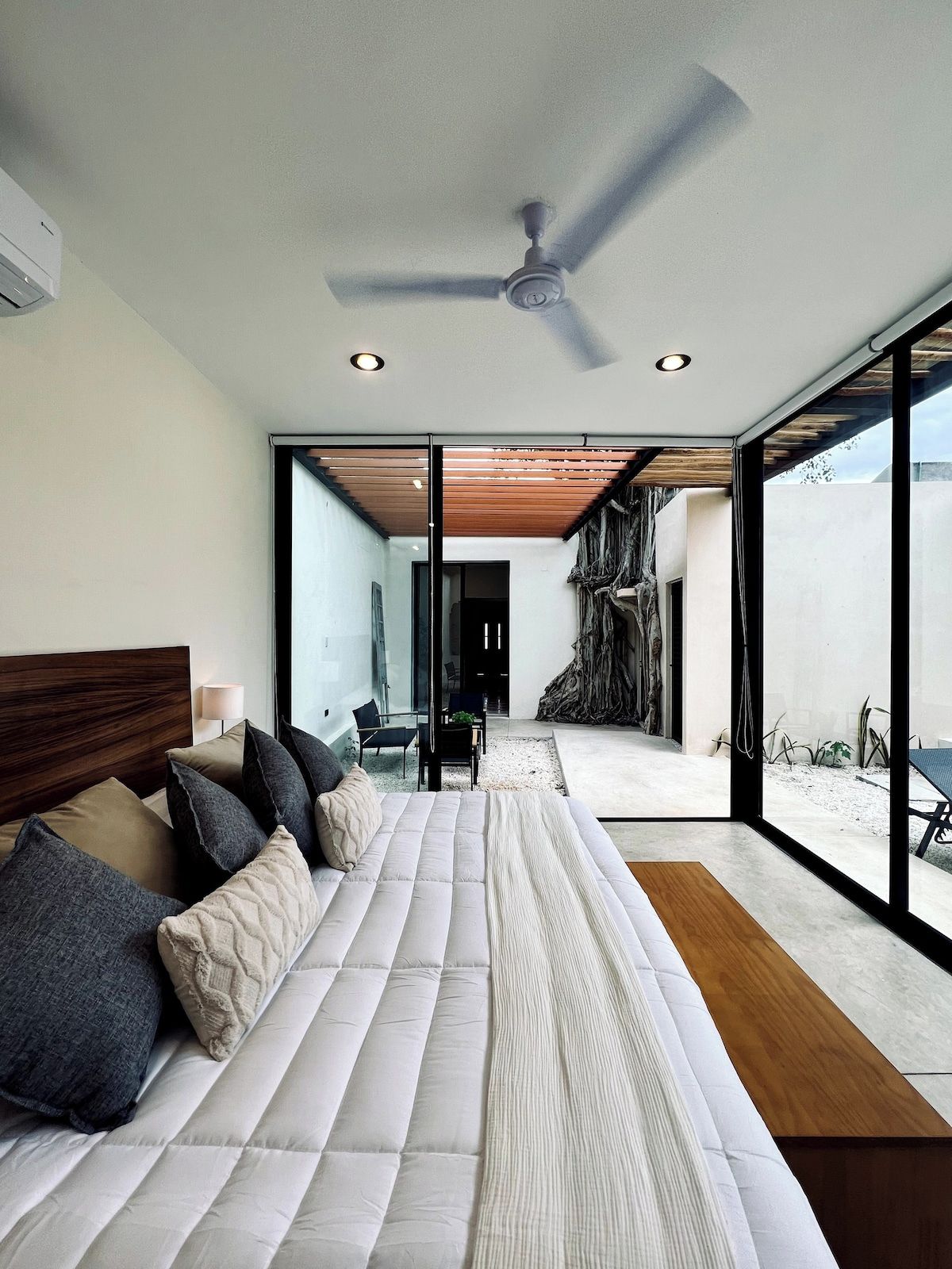 Un dormitorio moderno con una cama grande, un ventilador de techo y vistas al exterior.