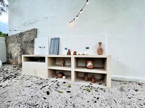 Un mur blanc orné d’étagères où sont exposées des poteries et un luminaire.