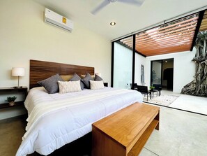 A modern bedroom with a large bed, a wooden bench, a nightstand, and a ceiling fan. - Casa Álamo in Downtown Mérida: 1br+Private Pool (Merida)