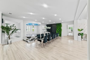 Un hall d’hôtel moderne avec une longue table à manger, des chaises et des plantes en pot.