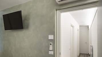 Ein Flur mit einer Wandklimatechnik, einem Flachbildfernseher an der Wand und einer Tür zu einem weiteren Zimmer.