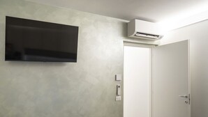 Habitació moderna amb televisió de pantalla plana penjada a la paret, una porta blanca i un aparell d'aire condicionat.
