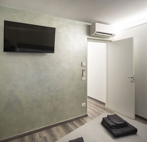 Une chambre moderne avec un téléviseur à écran plat fixé au mur, une porte blanche et un appareil de climatisation.