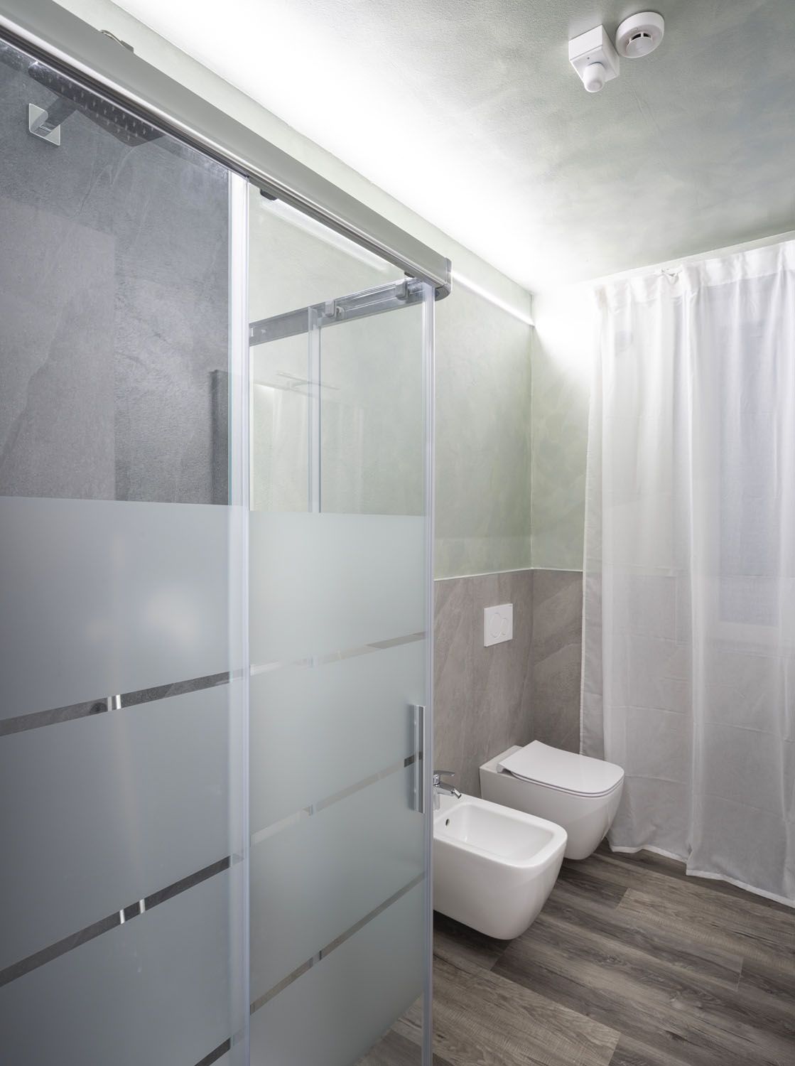 Een moderne badkamer met een douchecabine van glas, een toilet en een bidet.