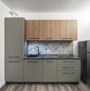 Eine Küche mit grauen Schränken, einem schwarzen Spülbecken und fliesenbesetzter Rückwand.