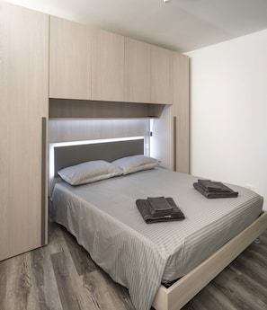 Un lit avec une tête de lit, une armoire en bois et un plancher en bois.