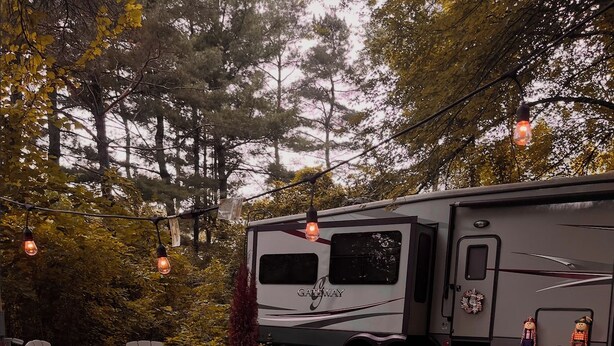Un terrain de camping équipé d’emplacements pour camping-cars, d’un espace extérieur aménagé pour s’asseoir et de parterres de fleurs.