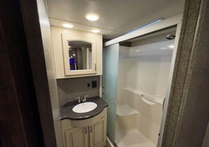 Ein kleines Badezimmer mit Waschbecken, Spiegel und Dusche.