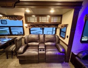 Ein gemütliches Interieur mit einem Ledersofa, einem Esstisch und einem Fenster mit Vorhängen.