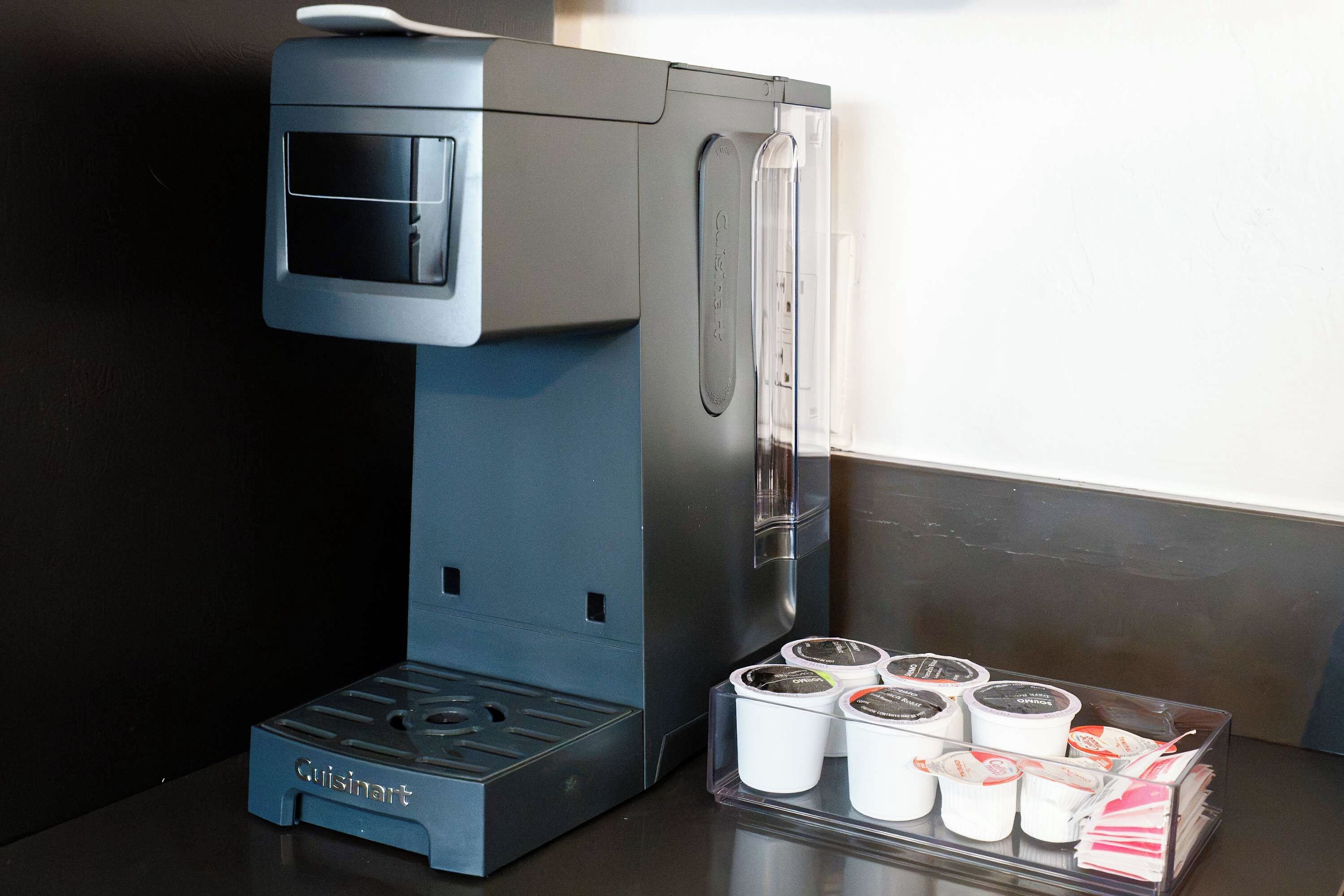 A Cuisinart coffee maker with a drip tray and several coffee pods.