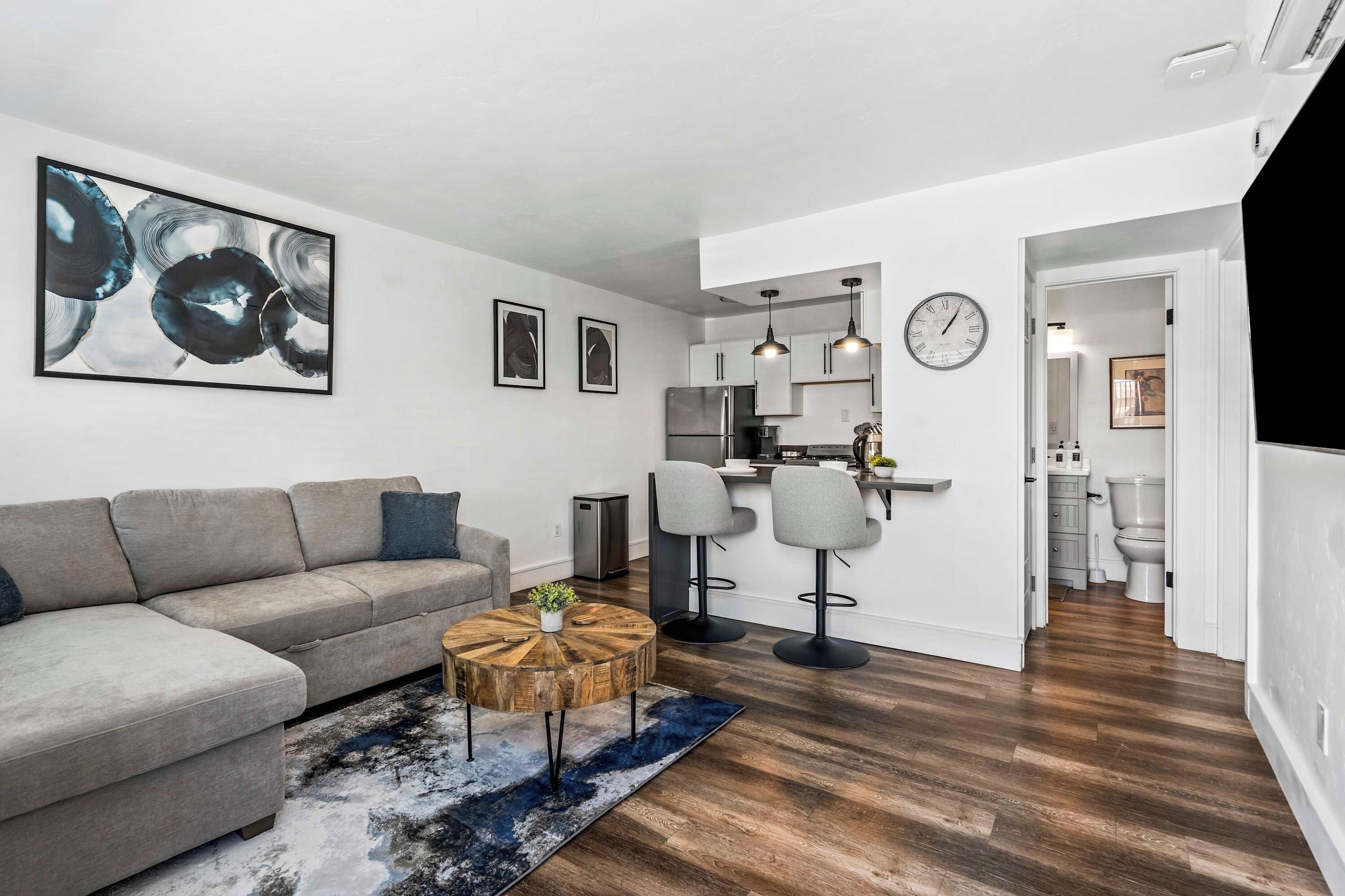 A modern living room with a grey sofa, a round coffee table, and abstract art on the wall.