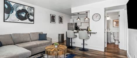 A modern living room with a grey sofa, a round coffee table, and abstract art on the wall.
