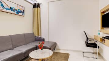 Un salon moderne avec un canapé gris, une table basse en marbre et un tableau accroché au mur.