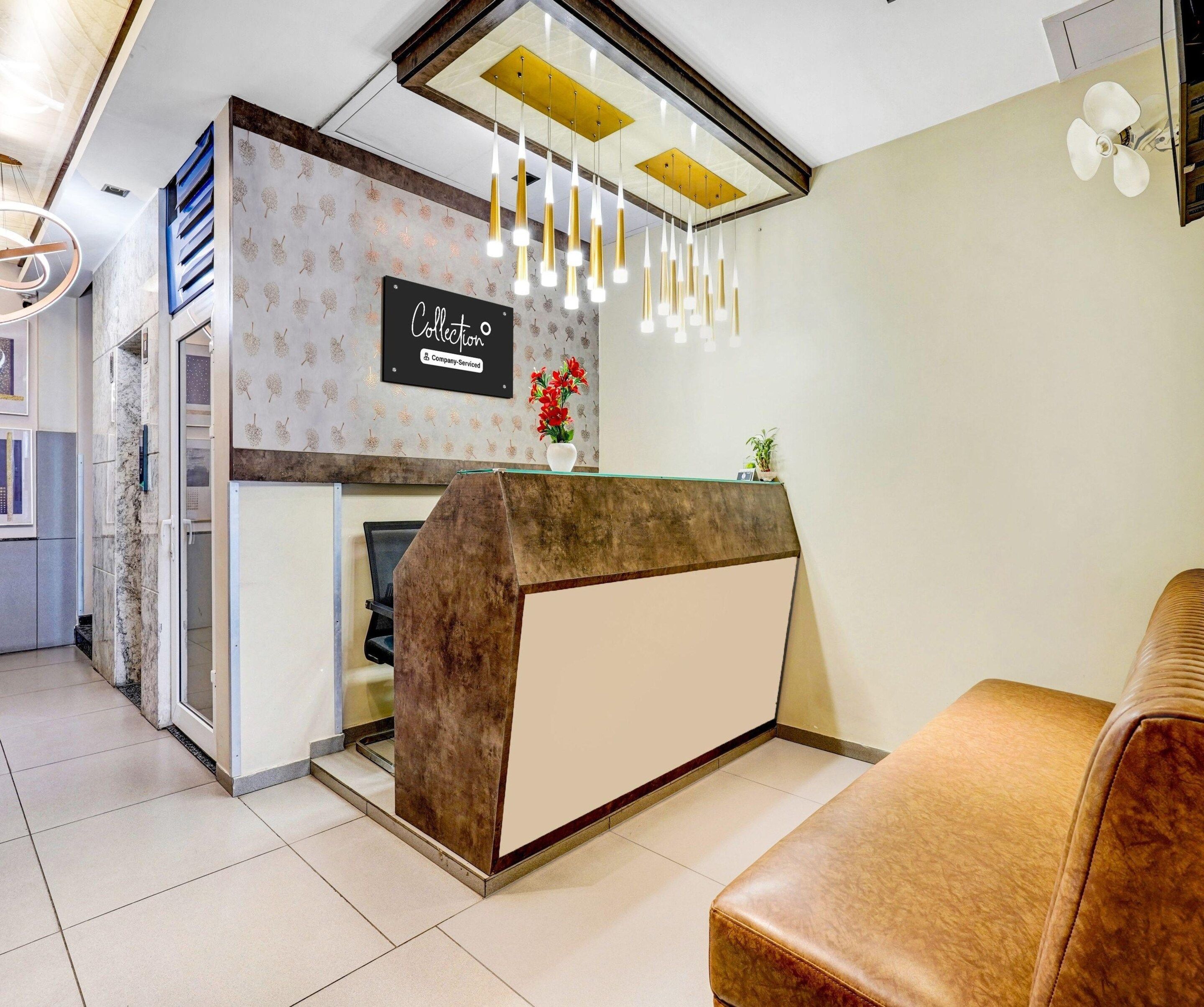 A reception area with a marble wall, a reception desk, a seating area, and a ceiling fan.