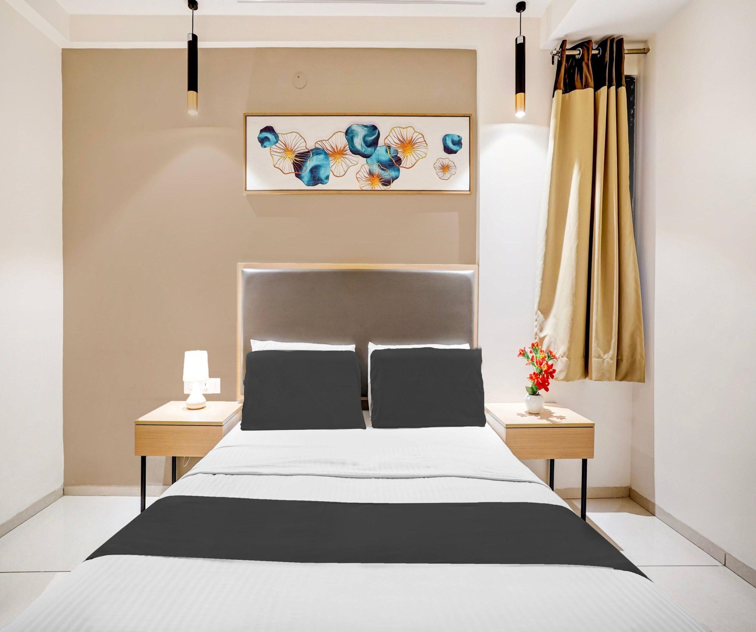 A modern bedroom with a large bed, two bedside tables, a wall-mounted artwork, and a window with curtains.