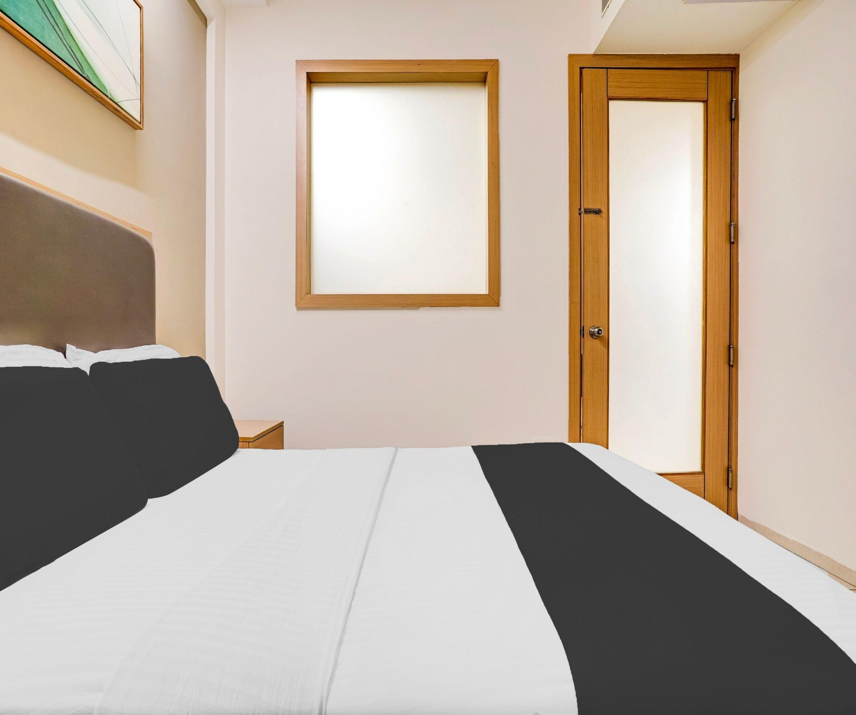 A bedroom with a bed, a nightstand, a window, and a door.