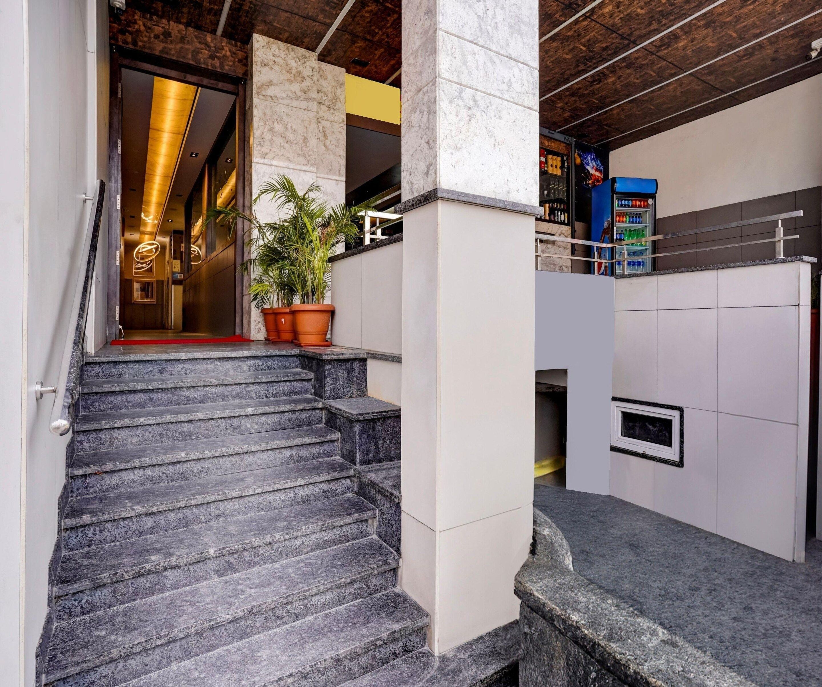 A staircase leading to a room with a marble wall and a vending machine.
