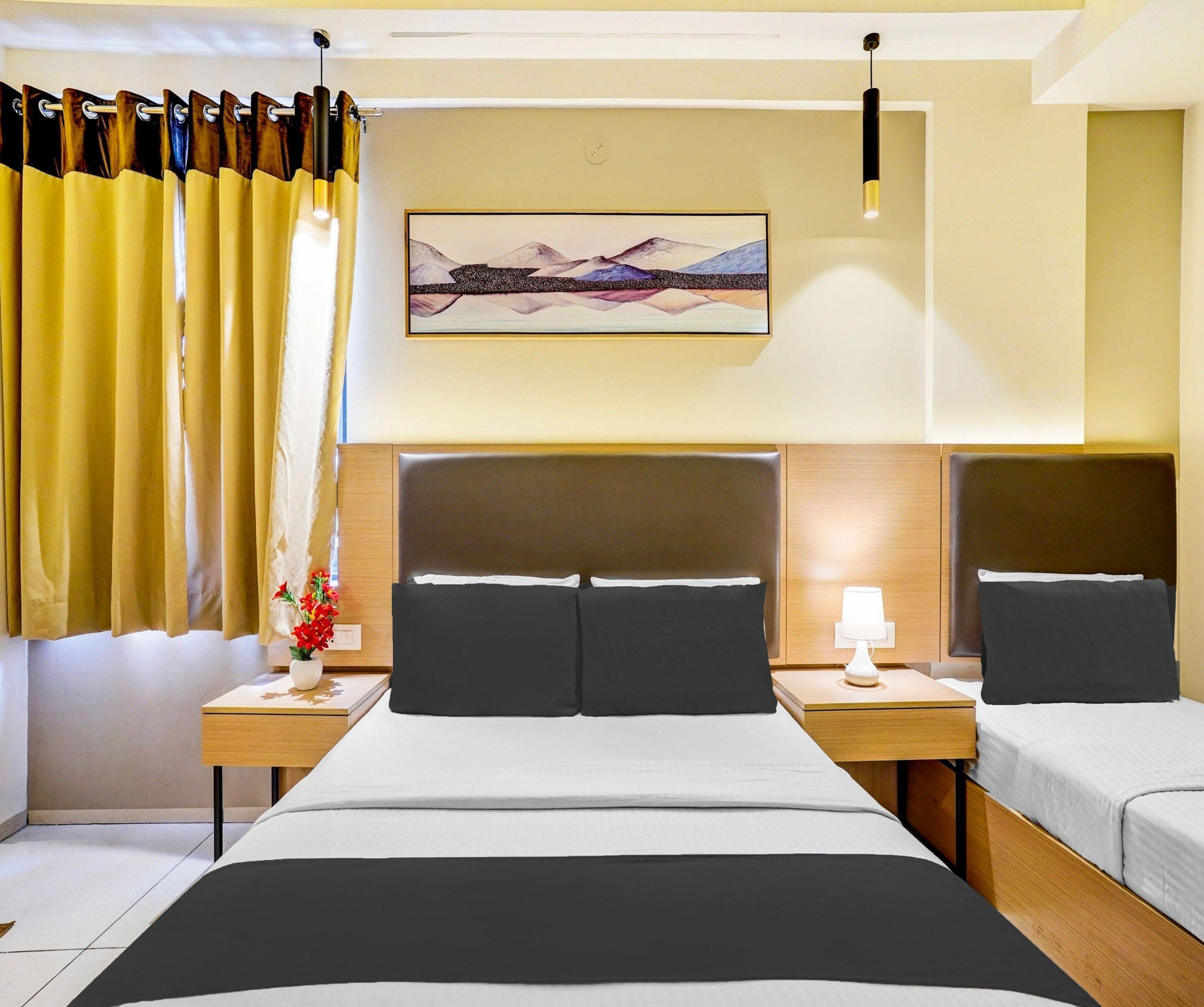 A hotel room with a large bed, two bedside tables, a nightstand with a lamp, a painting on the wall, and a window with curtains.