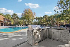 Un área de piscina al aire libre con una parrilla y un bar de piedra.