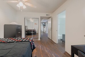 Un dormitorio con cama, armario, puerta que da a un baño y pasillo.