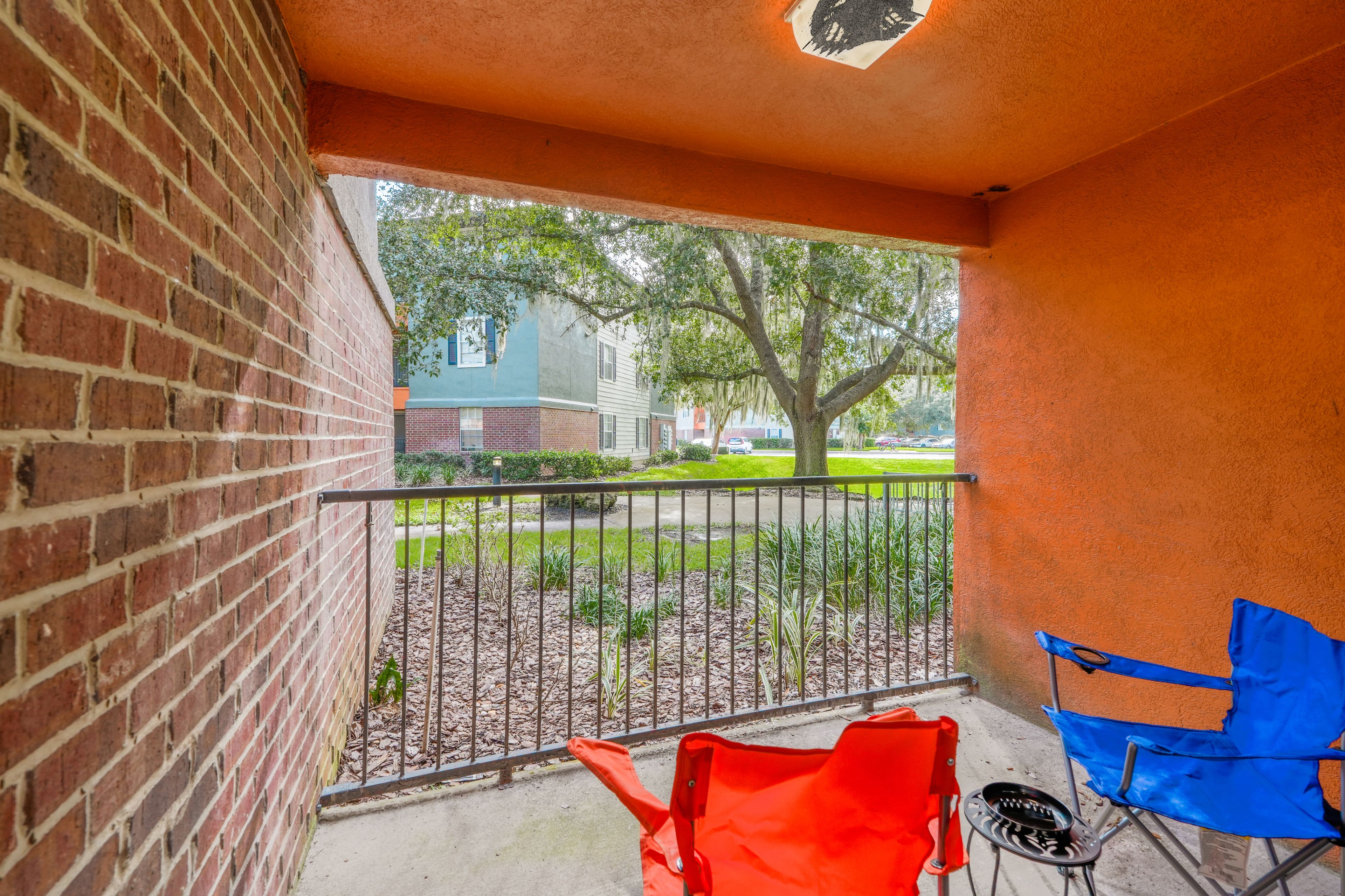 Een balkon met een bakstenen muur, een metalen hekwerk en twee stoelen.