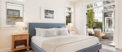 A bedroom with a large bed, bedside tables, a window, and a view of the outdoors.