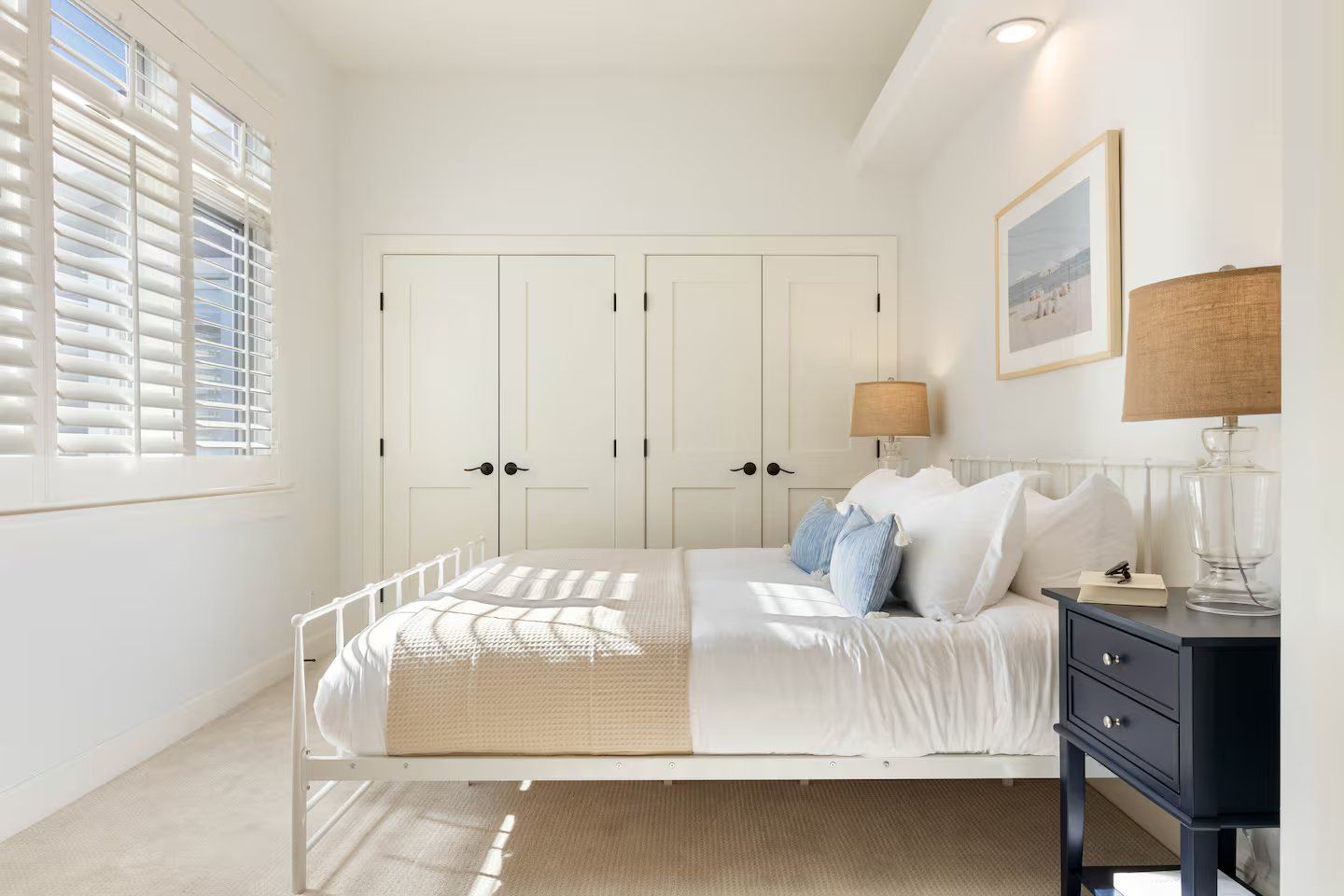 Une chambre à coucher avec un lit, une table de chevet, une lampe et un tableau encadré au mur.
