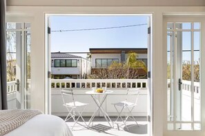A balcony with a white railing, two white chairs, and a small round table with a bowl of fruit. - Mins To Newport Beach, Pier, Water-Front Dining (Newport Beach)