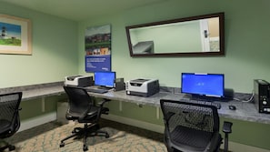 A room with two desks, each with a computer, printer, and chair.