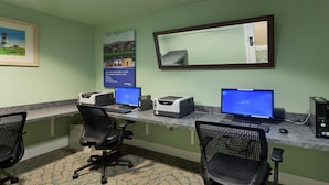 Ein Zimmer mit zwei Schreibtischen, jeweils mit Computer, Drucker und Stuhl.