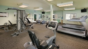 A gym with cardio machines, weight stations, and exercise balls.