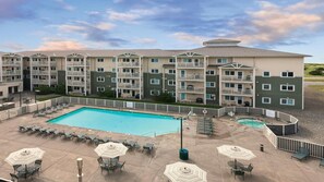 A hotel with a swimming pool, outdoor seating, and multiple balconies.