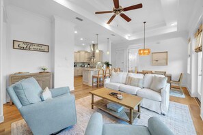 A spacious living room with a sofa, armchairs, a coffee table, and a ceiling fan. - Coastal Social by Stay on 30a (Watersound)