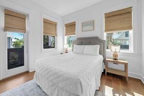 A bedroom with a large bed, two bedside tables, and three windows with blinds. - Coastal Social by Stay on 30a (Watersound)