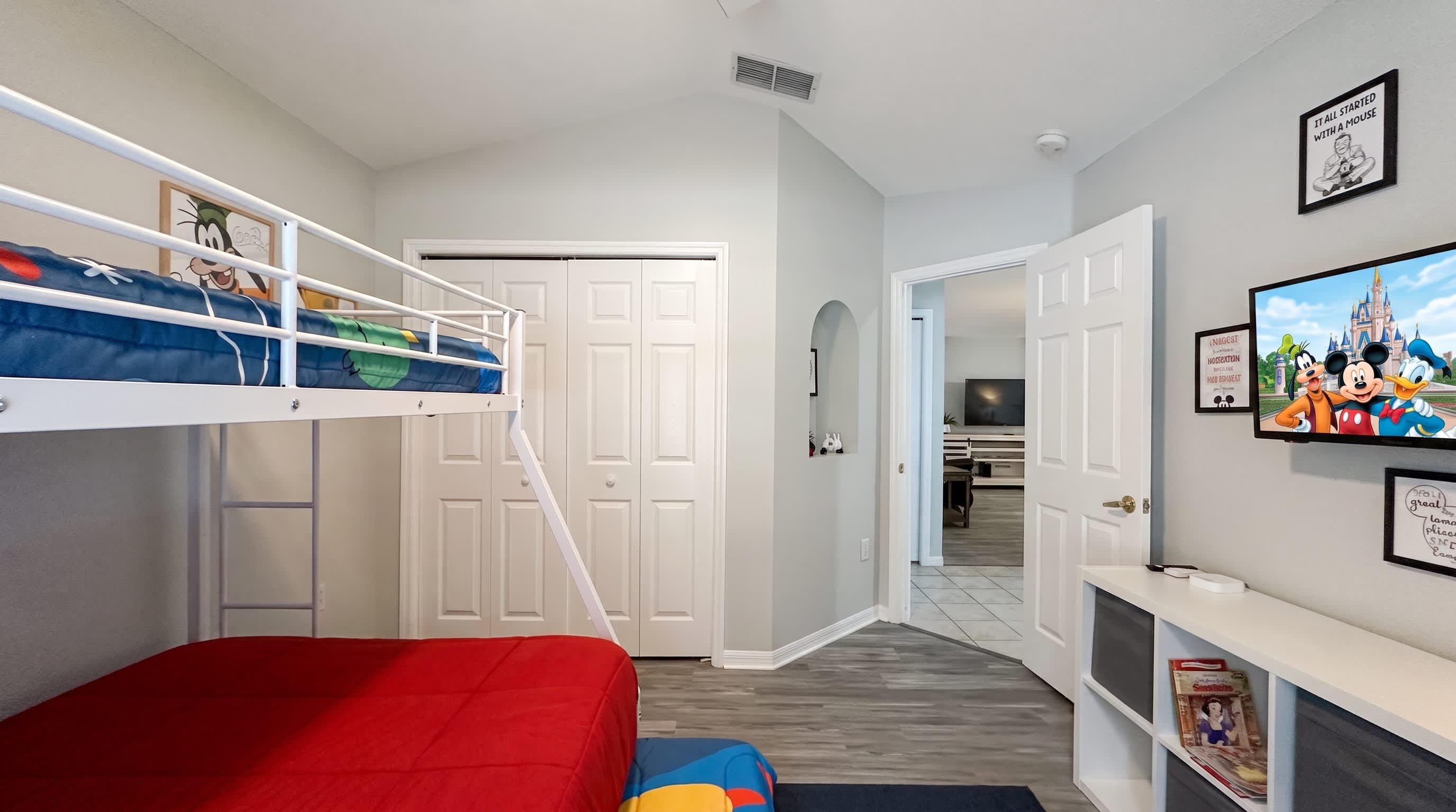 Une chambre d’enfant avec des lits superposés, une télévision et des décorations sur le thème de Disney.