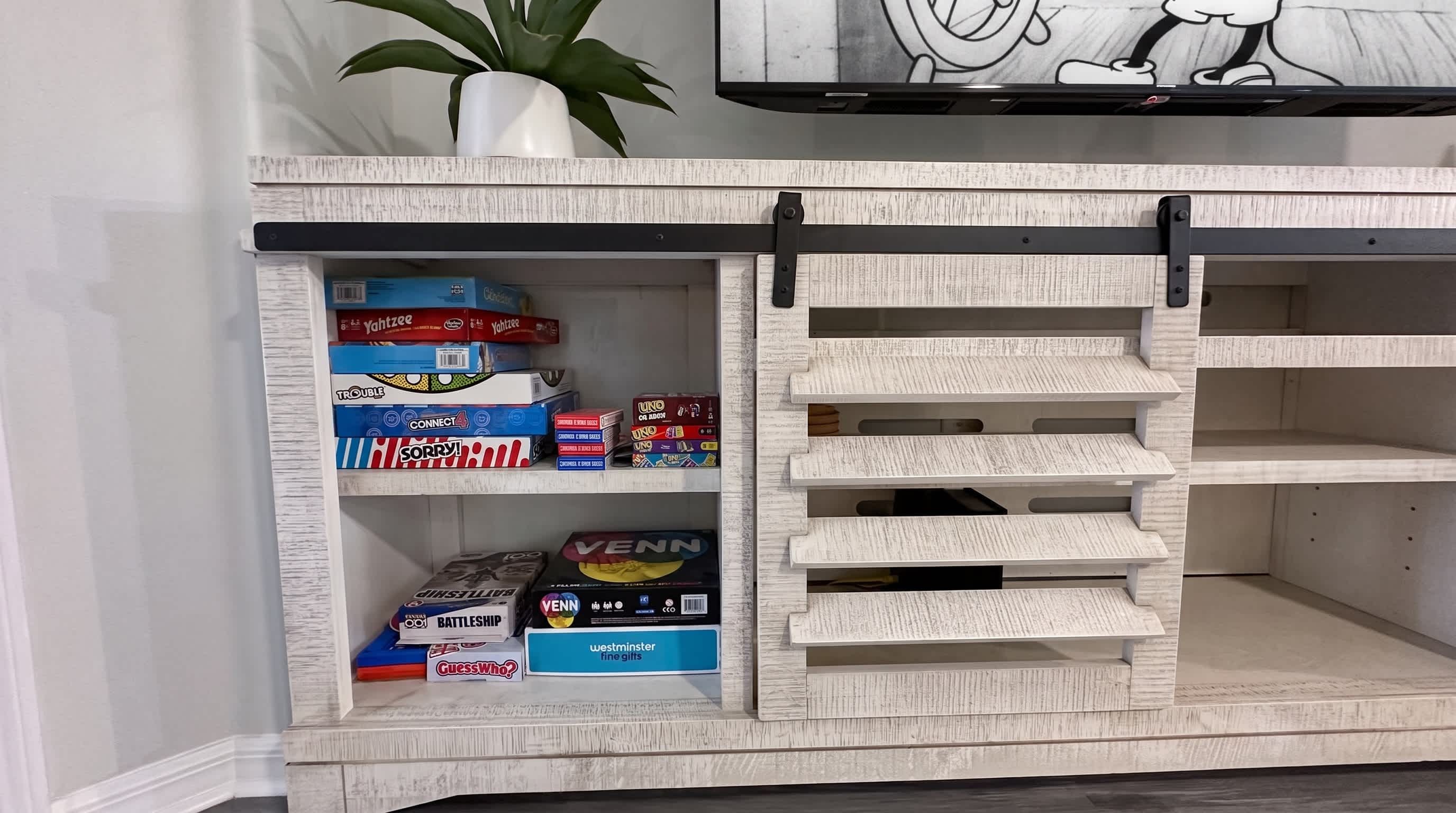 A shelf with board games and a potted plant.