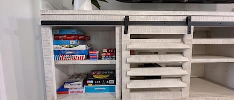 A shelf with board games and a potted plant.