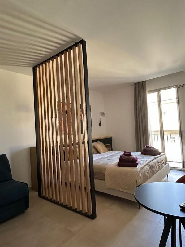 A hotel room with a bed, a desk, a chair, and a window.