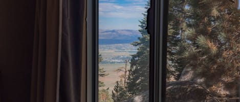 Vista desde una ventana a un paisaje montañoso con cielo despejado.